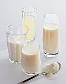Glasses of buttermilk, kefir, whey and whole milk with spoon of milk powder