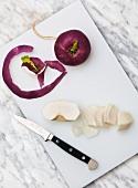 Horseradish and root vegetable on cutting board with knife, overhead view
