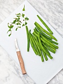 Runner beans on cutting board with knife, overhead view