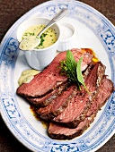 Slices of roast beef with bearnaise sauce bowl on plate