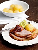 Roast pork slices with caraway seeds, cabbage and dumplings on plate
