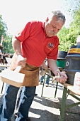 Senior man fitting tap in wine barrel in Franconian Switzerland, Bavaria, Germany