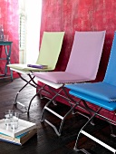 Folding chairs with colourful felt cushions against red wall