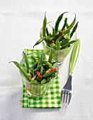 Glasses of green beans with garlic on checked tablecloth