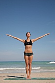 Frau bei Yogaübung am Strand Fitness-Übung