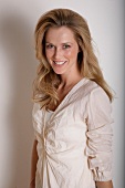 Portrait of pretty blonde woman wearing beige blouse, smiling