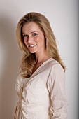 Portrait of pretty blonde woman wearing beige blouse, smiling