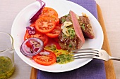 Close-up of lamb streaks with thyme pesto and tomato salad on plate