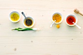 Four different salad dressings in small bowls with spoons, overhead view