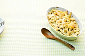 Cheese macaroni in serving dish with wooden spoon