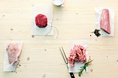 Four different raw meat on baking paper, overhead view