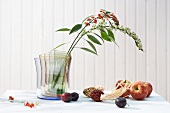 Autumnal decoration with fruit and flower in a designer vase on table