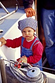 Portrait of sailor's child standing on sailboat in Munkmarsch, Sylt, Germany
