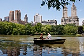 Couple on boat at Central park lake overlooking The Dakota, New York, USA