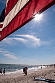 American flag waving with people enjoying on beach, New York, USA