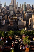 View of cityscape overlooking people sitting on rooftop bar at New York, USA