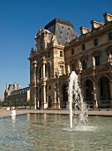 Facade of Louvre Museum with fountain in Paris, France