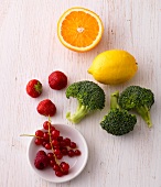 Lemon, oranges, broccoli and berries on wooden surface - food rich in vitamin C