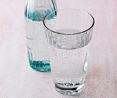 Close-up of glass and bottle filled with mineral water