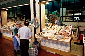 Fish stall in the market hall of Lisbon with customers buying fish