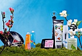 Various cosmetic and personal care products on moss with flowers, digital composite