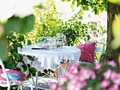 Crockery and glasses on a table in a summery garden