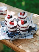 Glasses filled with yoghurt cream topped with berries on tray in summer kitchen