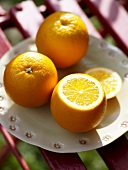 Sliced and whole oranges on plate, close-up