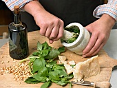 Mashing basil with pine nuts and oil in mortar