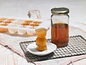 Frozen cubes of honey stacked on plate with honey in glass jar
