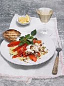 Grilled peppers with feta cheese on plate beside wine glass 