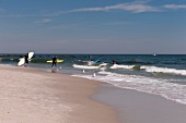 Man holding surfboard at Long Beach in New York, USA