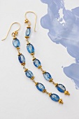 Close-up of long blue earrings made up of sapphires on white background