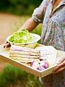 Woman holding tray with asparagus, lettuce and turnips, France