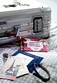 Silver suitcase and homemade luggage tags on bed