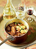 Beef bourguignon in pot with glasses of wine, France