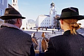 Rear view of two man and woman sitting in horse cab, Salzburg, Austria