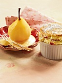 Pear with sabayon on saucer and souffle with candied fruits in ramekin