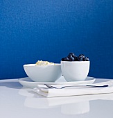 2 weiße Schalen auf Tisch vor blauer Tapete
