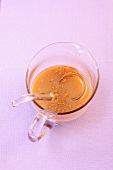 Caramel sauce in glass cup with spoon, overhead view