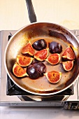 Quartered common figs being fried in pan