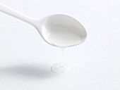 Sugar syrup being poured with spoon on white background