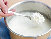 Adding cream to blended broth in pan for preparation of sauce, step 4