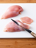 Slicing chicken on chopping board for preparation of chicken cutlet, step 1