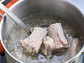 Close-up of beef pieces in ladle for preparation of beef stock, step 1