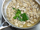 Close-up of herbs and mushrooms being boiled in pan for reduction, step 3