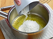 Flour being added in pan for preparation of white roux, step 2