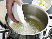 Flour being added in saucepan for preparation of bechamel sauce, step 1