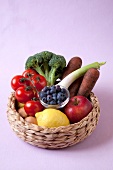 Broccoli, tomatoes, lemon, garlic, onions, apples and blueberries on pink background