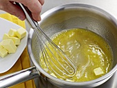 Butter being whisked in saucepan for preparation of white butter sauce, step 2